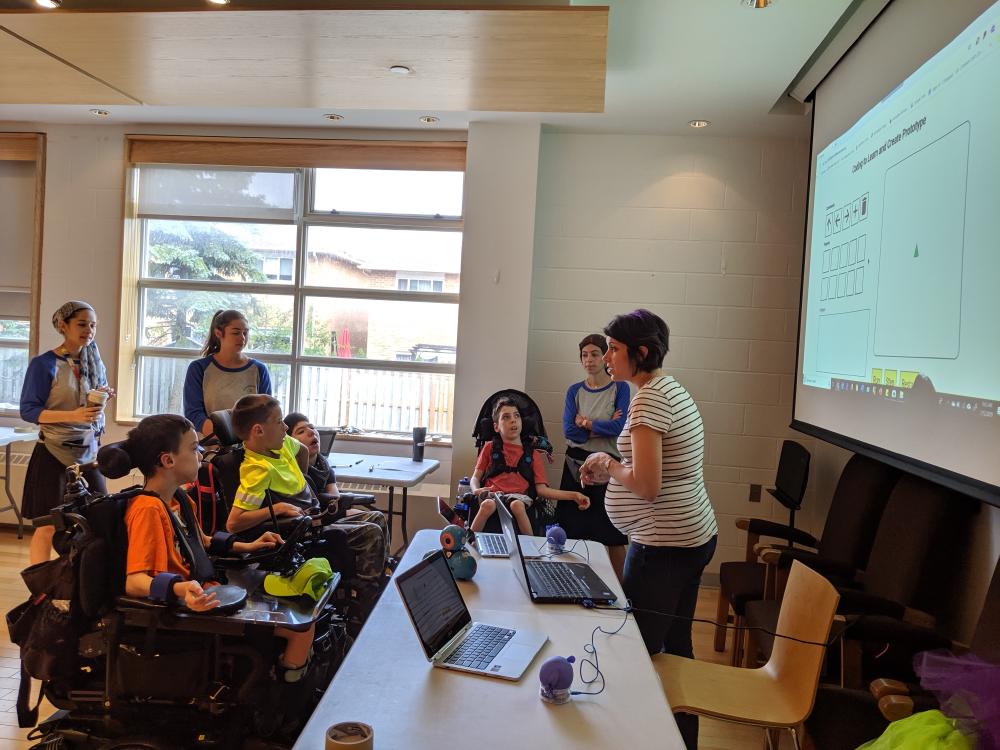 Prototype is projected on the screen and a facilitator is explaining its different sections to campers.