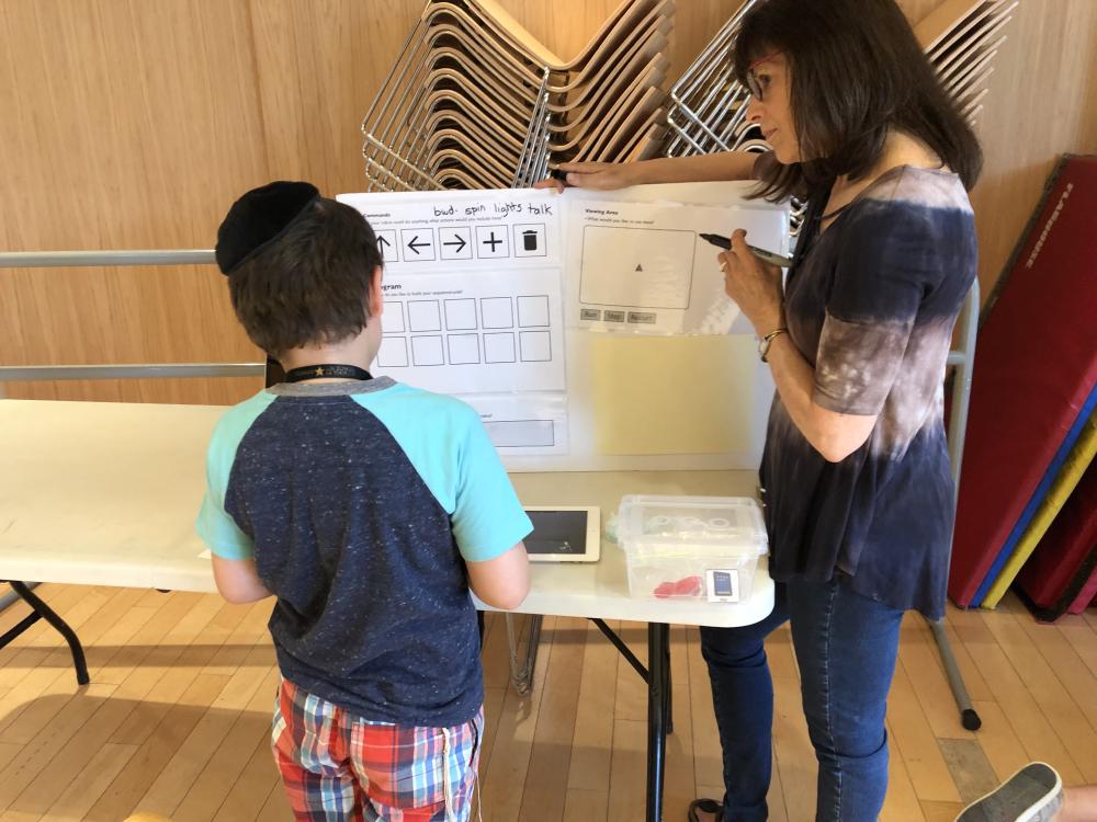 Camper designing his own coding interface on Styrofoam board with guidance from team facilitator.