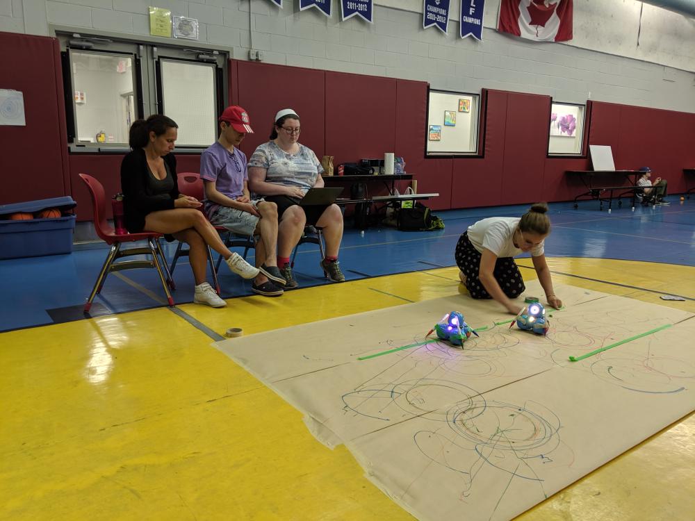 Campers coding sequences to create art with markers and Dash the robot.
