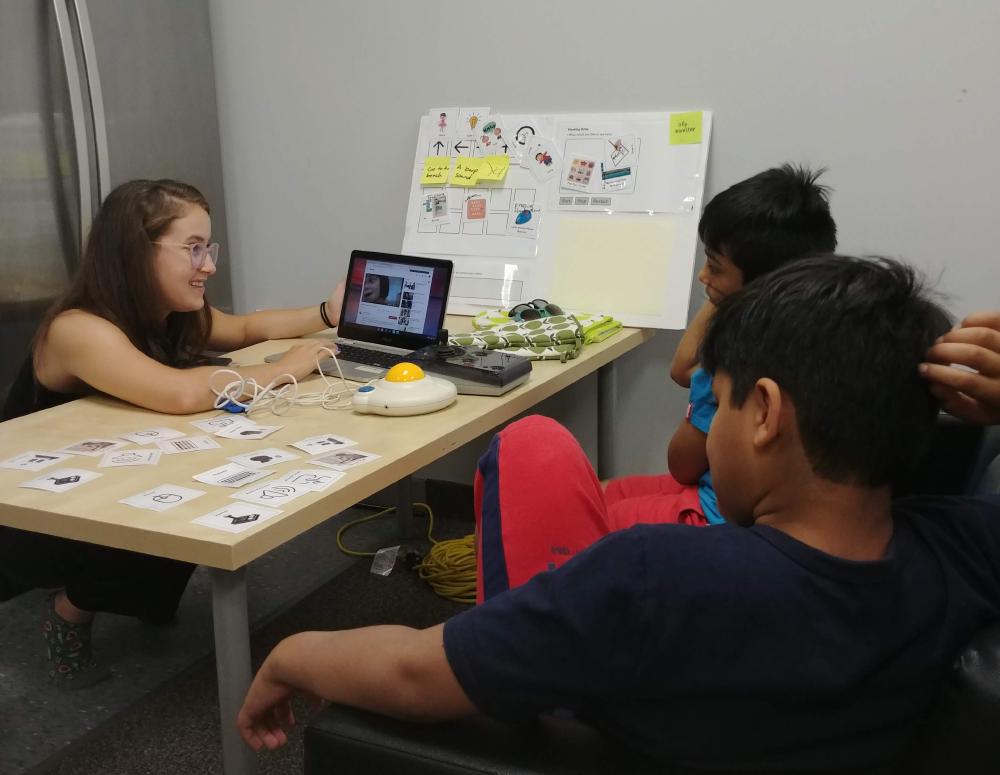 Campers watch a video of an eye-gaze system with a facilitator.